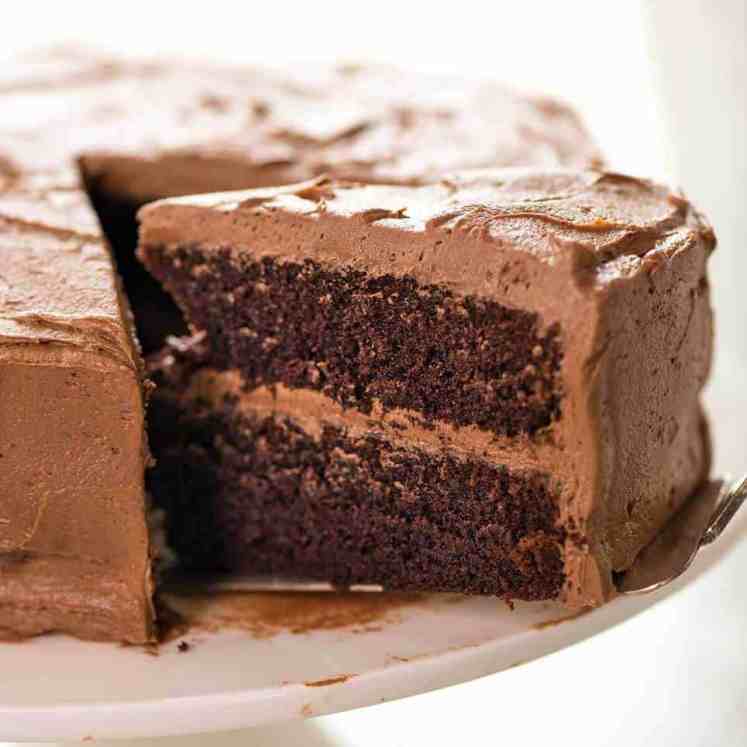 这张照片显示的是在一个白色的蛋糕架上有半块巧克力奶油糖霜的巧克力蛋糕，其中有一大块被拉了出来。