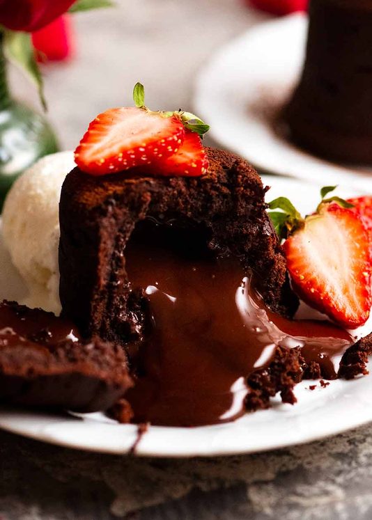 融化的巧克力蛋糕，巧克力熔岩涌出，点缀着草莓和一勺冰淇淋gydF4y2Ba